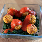 Boulettes de thon au quinoa servies sur un lit d’épinards avec sauce tomate maison et parmesan, recette anti-cholestérol équilibrée.