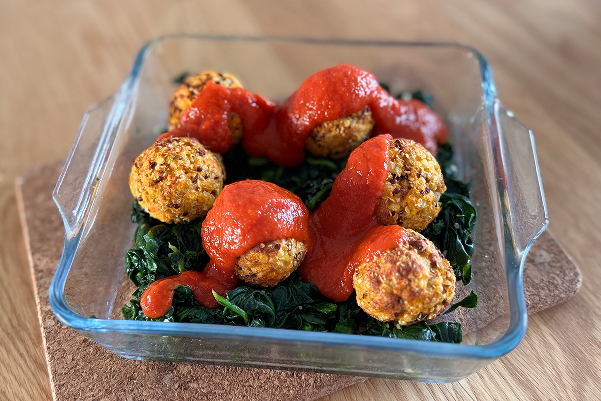 Boulettes de thon au quinoa servies sur un lit d’épinards avec sauce tomate maison et parmesan, recette anti-cholestérol équilibrée.