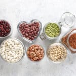 Assortiment de légumineuses et de céréales complètes riches en fibres alimentaires dans des bocaux et bols en verre